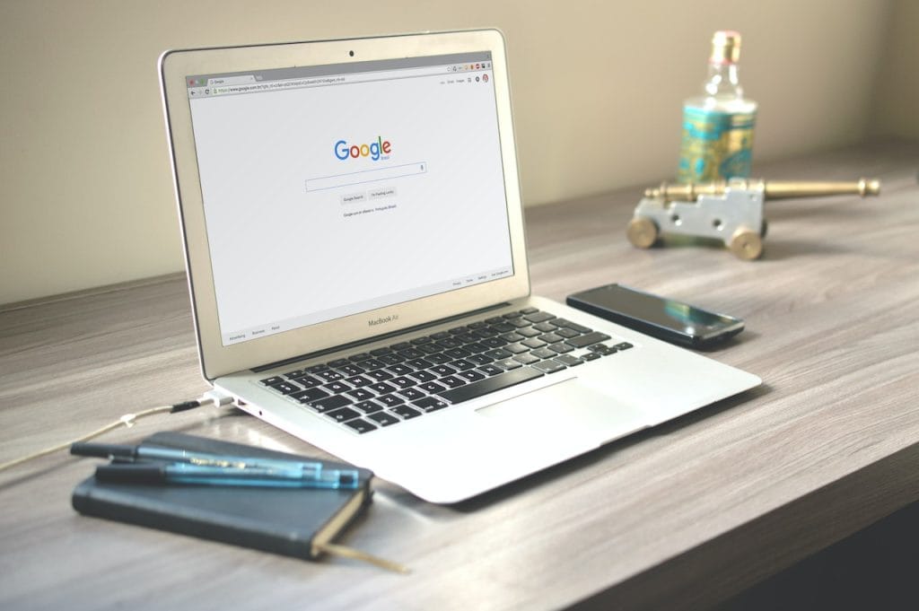 Laptop showing Google on desk with notebook, phone, and workspace items