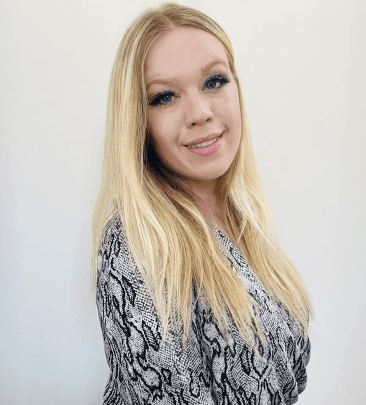 Smiling blonde woman in patterned top against white background