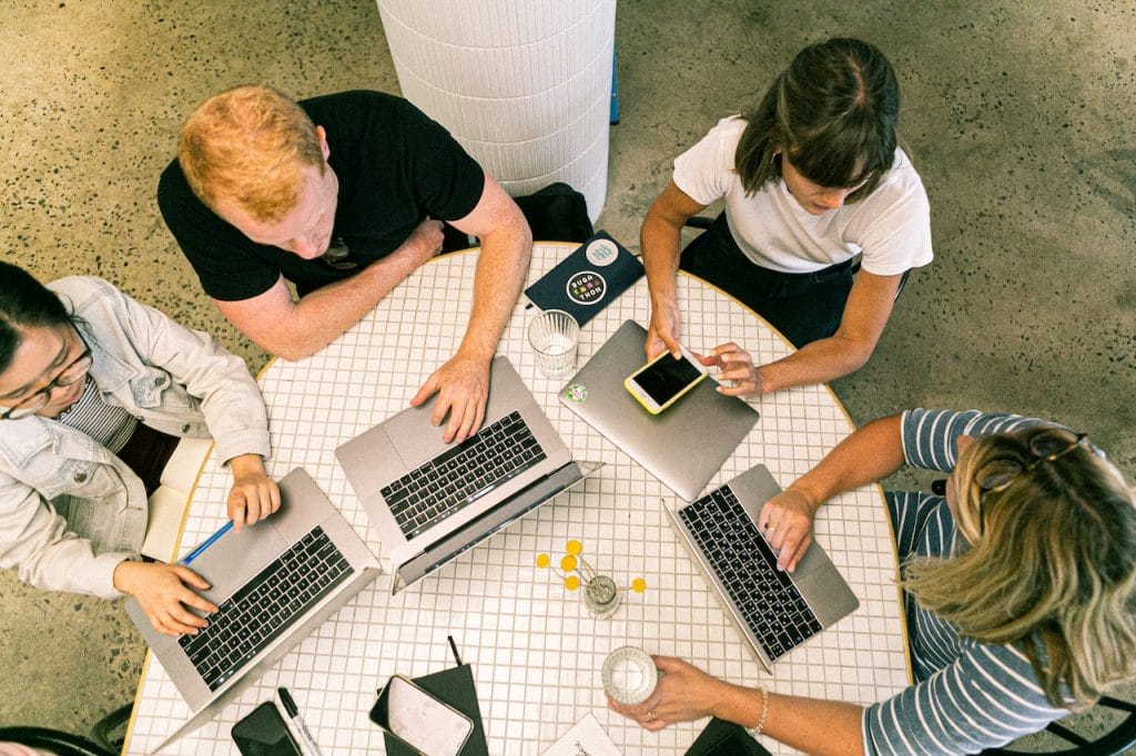 Group working with laptops and phone at table with drinks