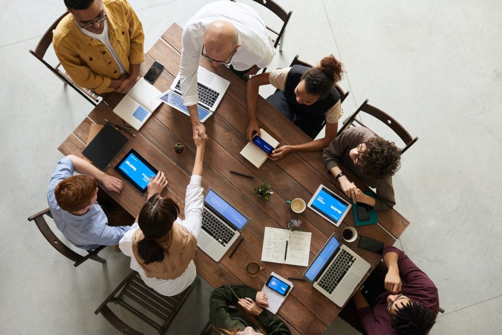 Meeting around table with handshake and laptops
