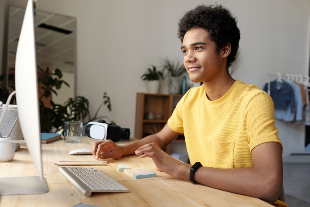 Young person smiling while working on computer at desk