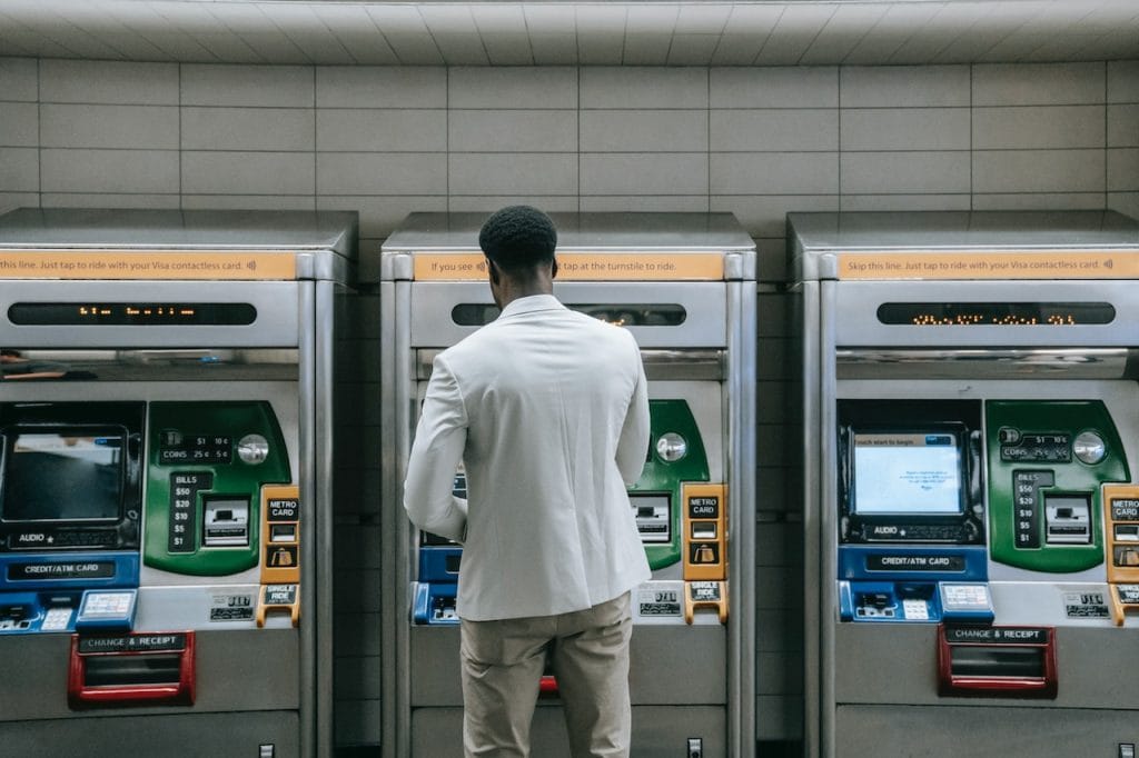 Person in white blazer standing near ATMs