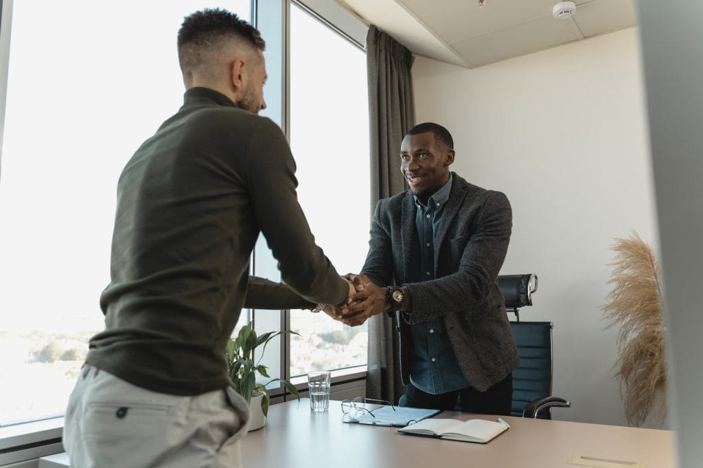 Two men shaking hands in office with plant