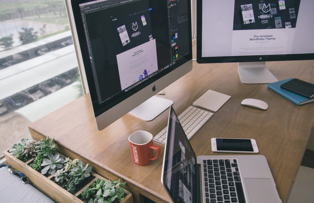 Workspace with monitors showing designs and laptop